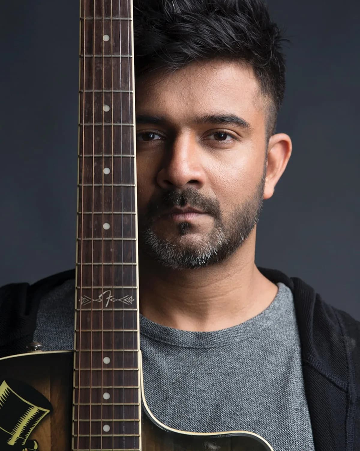 Sachin Sanghvi with an acoustic guitar, studio portrait